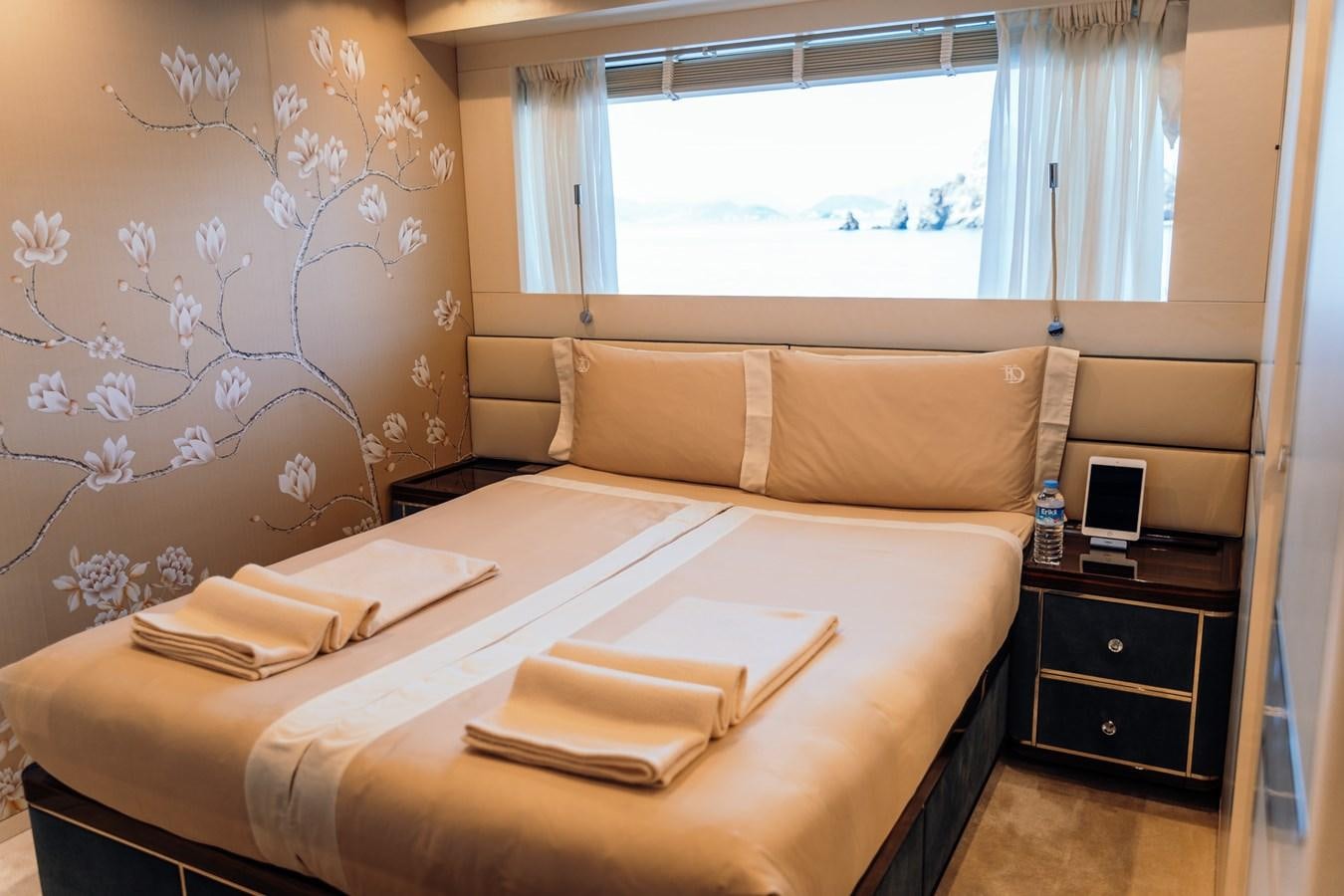 a bed with a white sheet and a brown pillow aboard ALULIM Yacht for Sale
