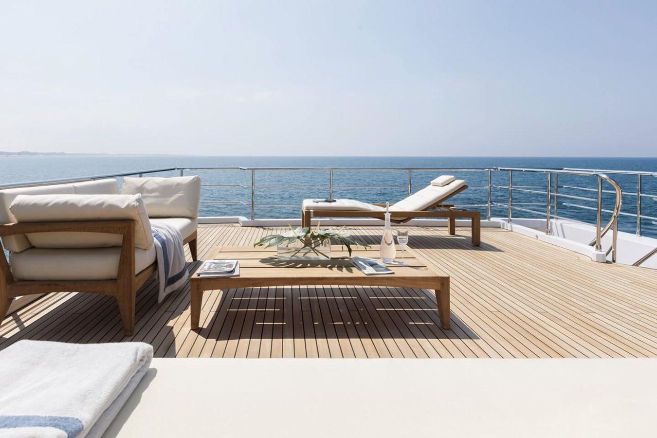 a lounge chair and a table on a deck overlooking a beach aboard 2019 AZIMUT GRANDE 35 M/Y HEED Yacht for Sale
