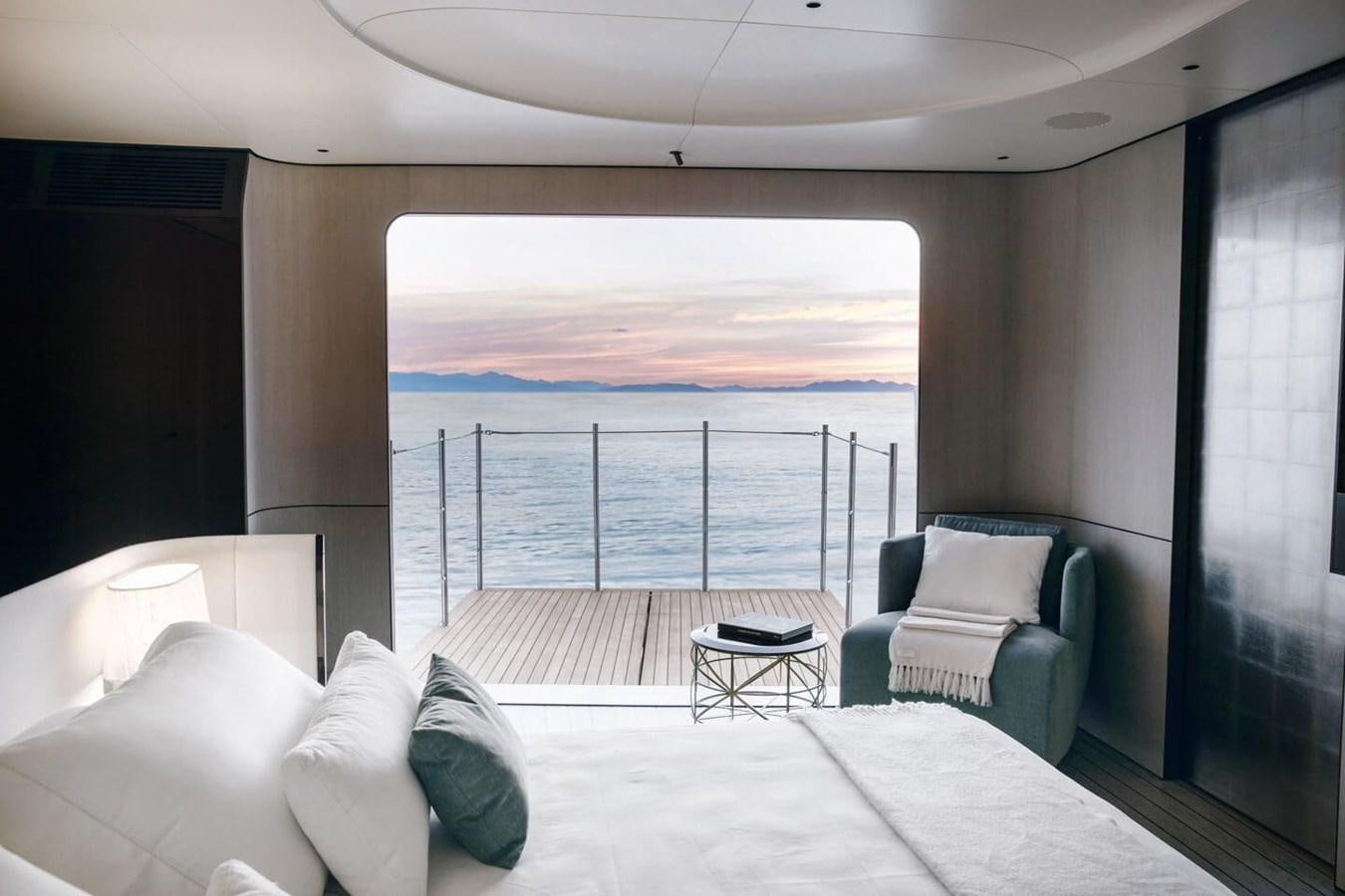 a bed and a chair in a room with a large body of water aboard 2019 AZIMUT GRANDE 35 M/Y HEED Yacht for Sale