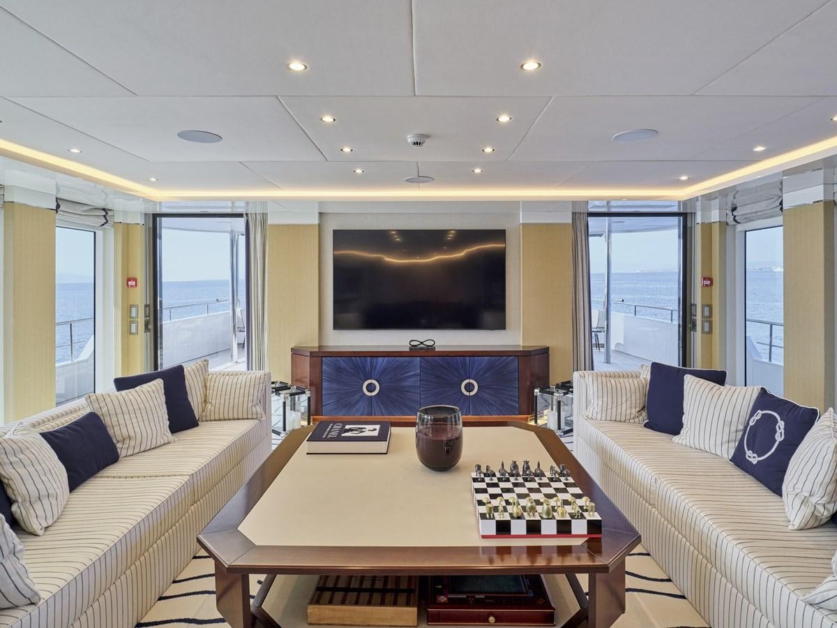 a living room with a tv and a table aboard AKULA Yacht for Sale
