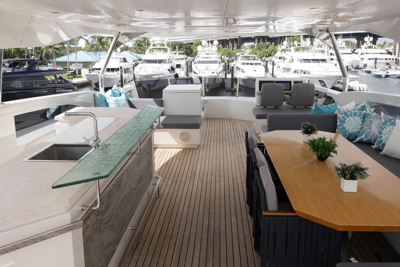 a room with a table chairs and a large window with a view of the water and boats in aboard KANDO Yacht for Sale