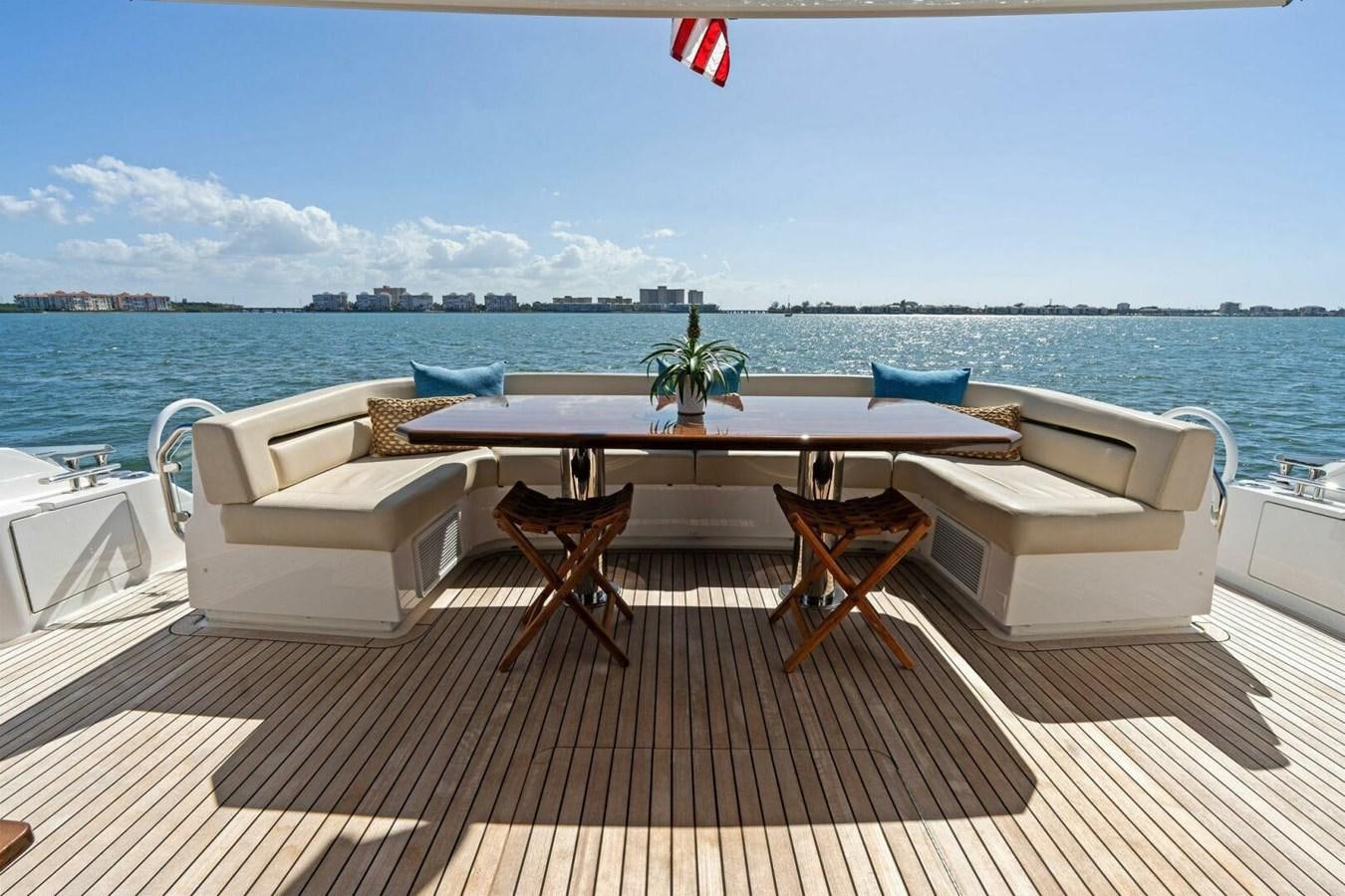 a table and chairs on a deck overlooking a body of water aboard MANA Yacht for Sale
