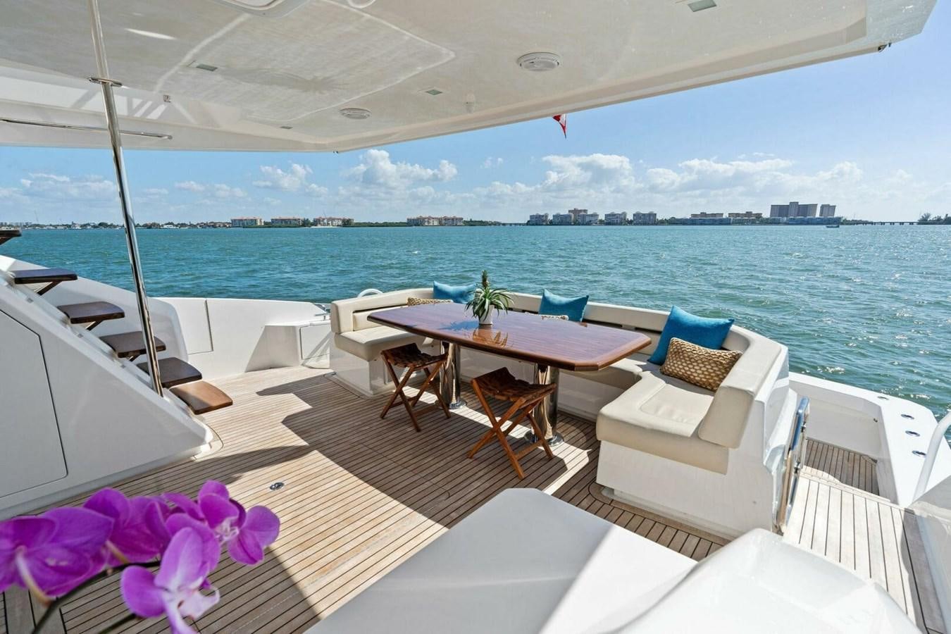 a deck with chairs and tables on it by the ocean aboard MANA Yacht for Sale