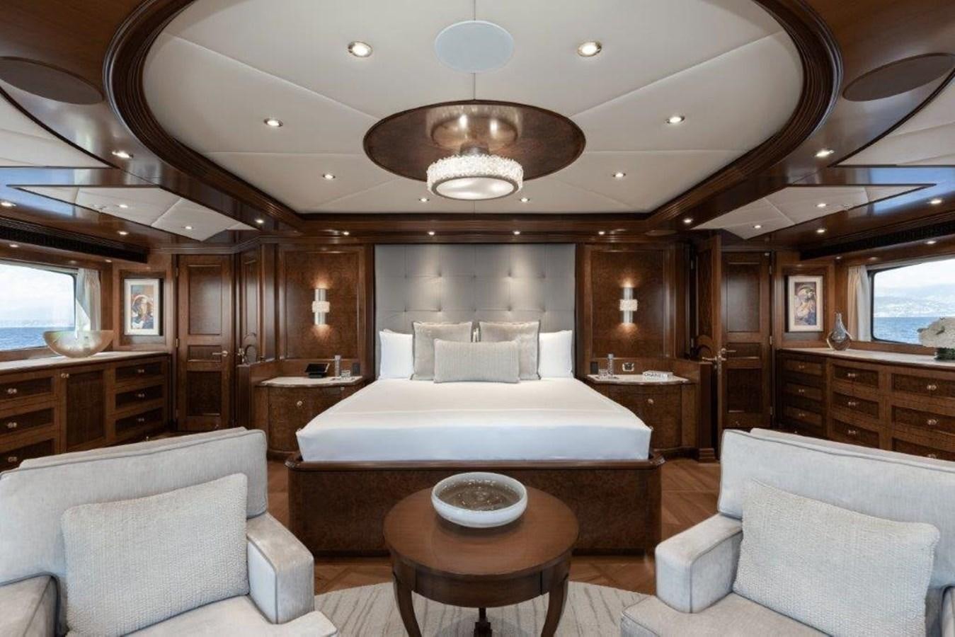 a large bedroom with a bed and a chandelier aboard IRON BLONDE Yacht for Sale