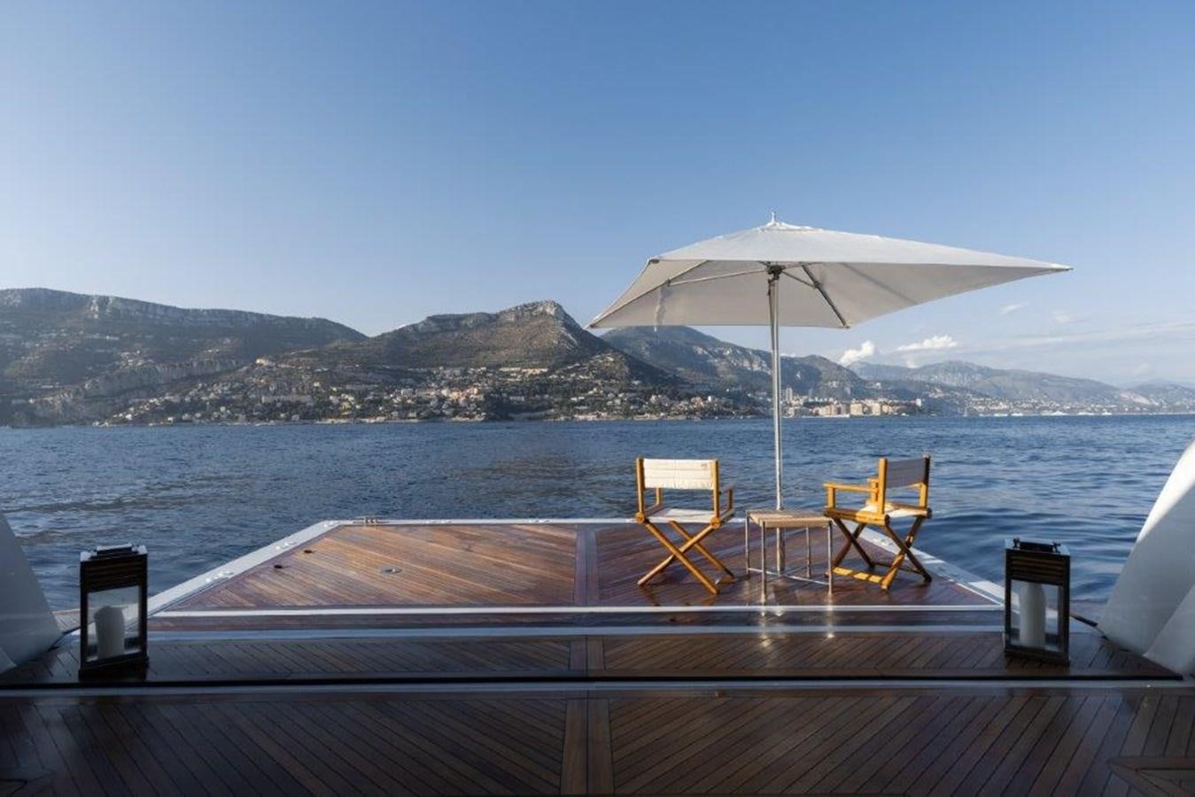 a deck with chairs and umbrellas on it by the water aboard IRON BLONDE Yacht for Sale