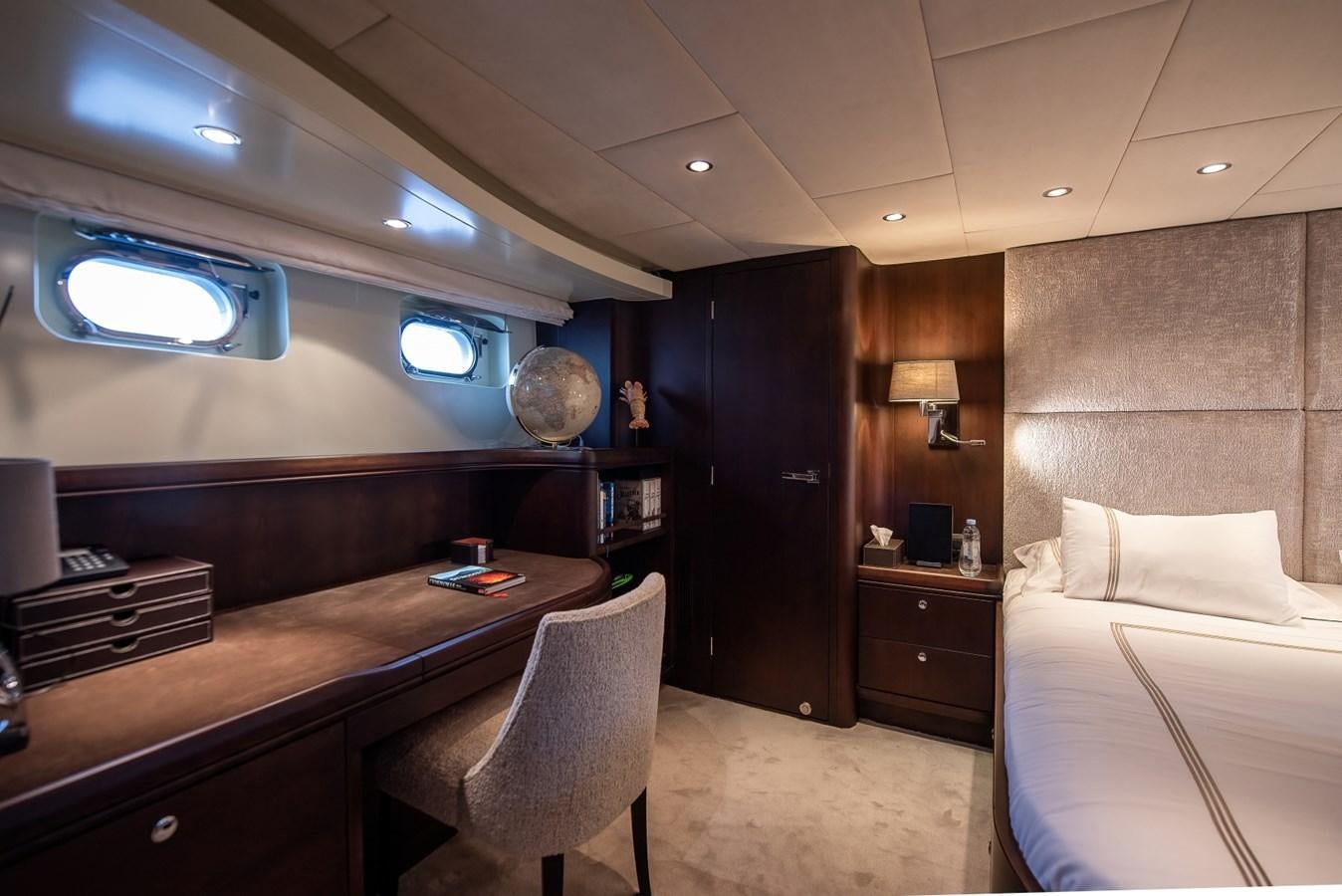a room with a bed and desk aboard NASHIRA Yacht for Sale