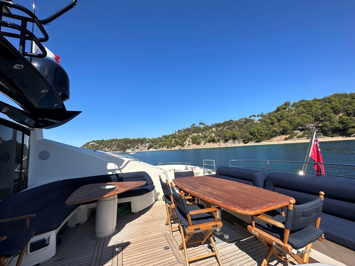 a deck with a table and chairs on it and a body of water in the background aboard LOW PROFILE Yacht for Sale