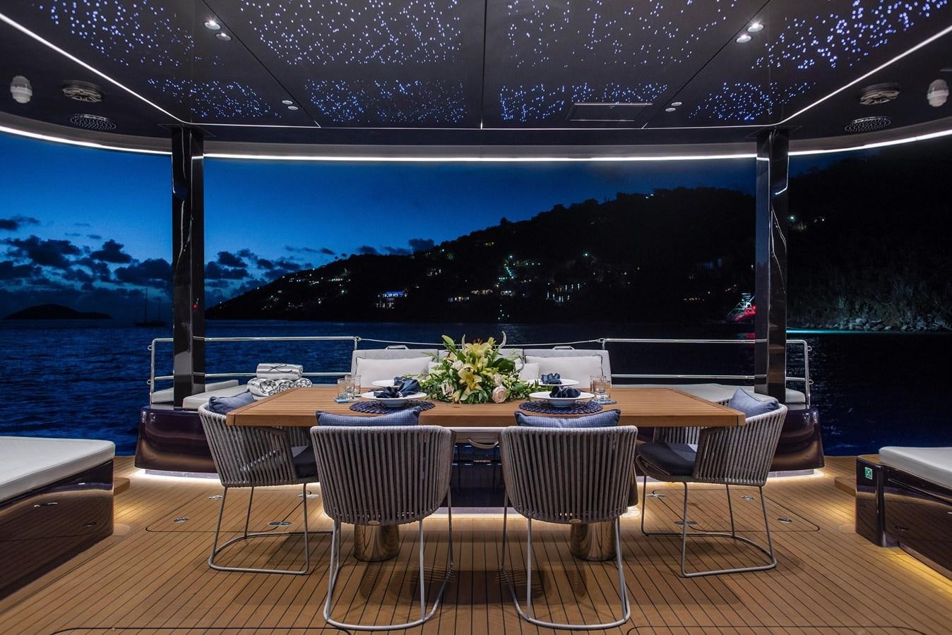 a table with chairs and a view of the ocean aboard 2022 SUNREEF 80 SAILING Yacht for Sale