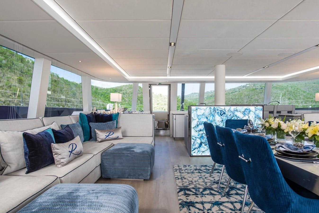 a living room with a blue chair and a blue chair aboard 2022 SUNREEF 80 SAILING Yacht for Sale
