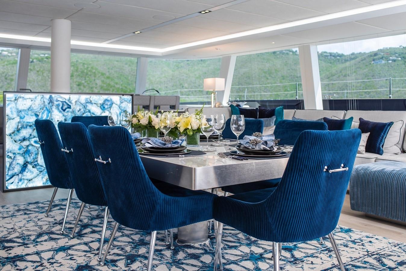 a table with chairs and a couch aboard 2022 SUNREEF 80 SAILING Yacht for Sale