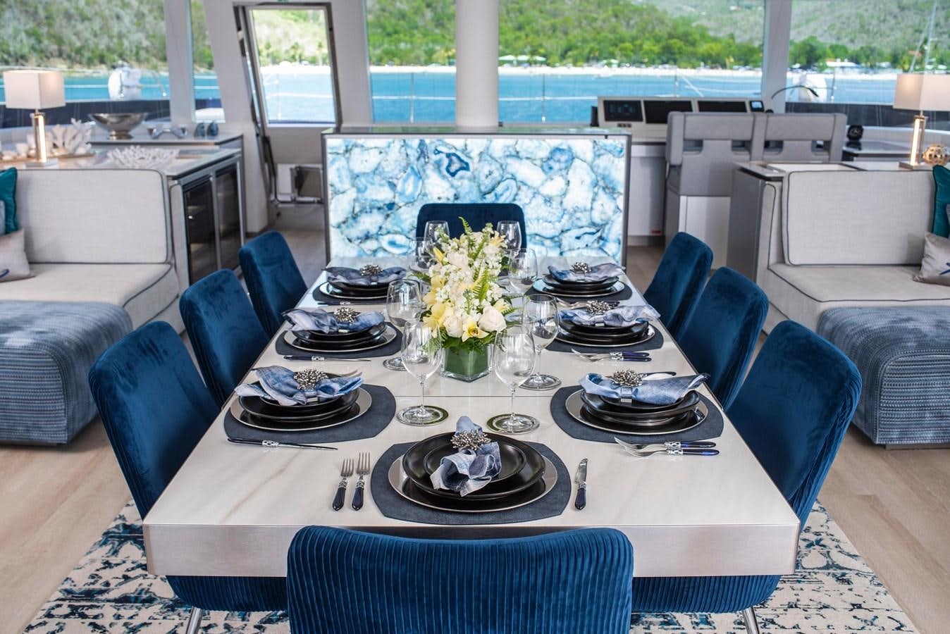 a dining table set with plates and flowers aboard 2022 SUNREEF 80 SAILING Yacht for Sale