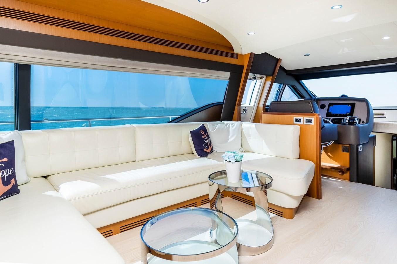 a white couch with a table and a chair in a room with a large window aboard HOPE Yacht for Sale