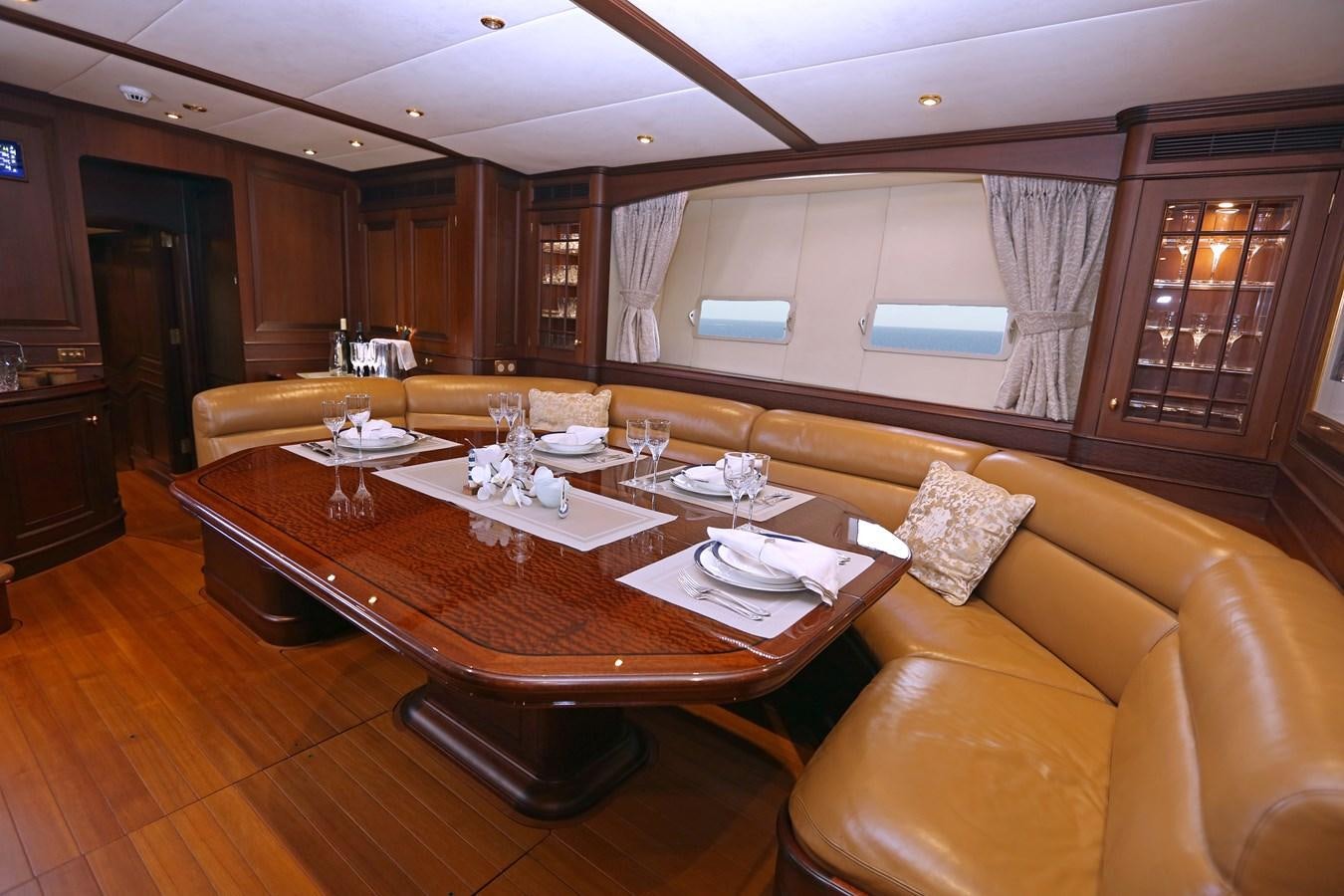 a large living room with a wood table and chairs aboard SOJANA Yacht for Sale