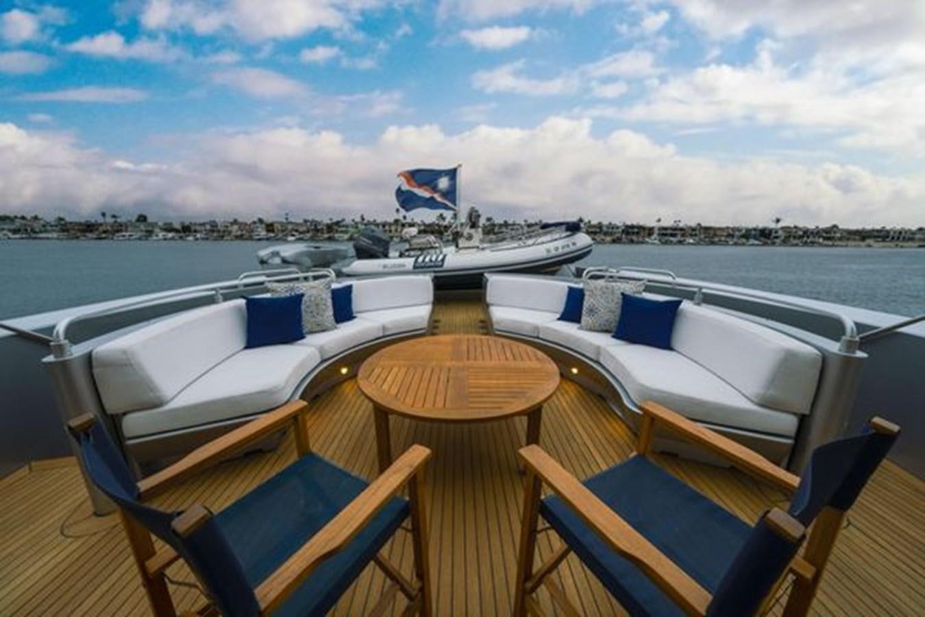 a table with chairs on it next to a boat on a body of water aboard 2003 BAGLIETTO 38M FAST FLY Yacht for Sale