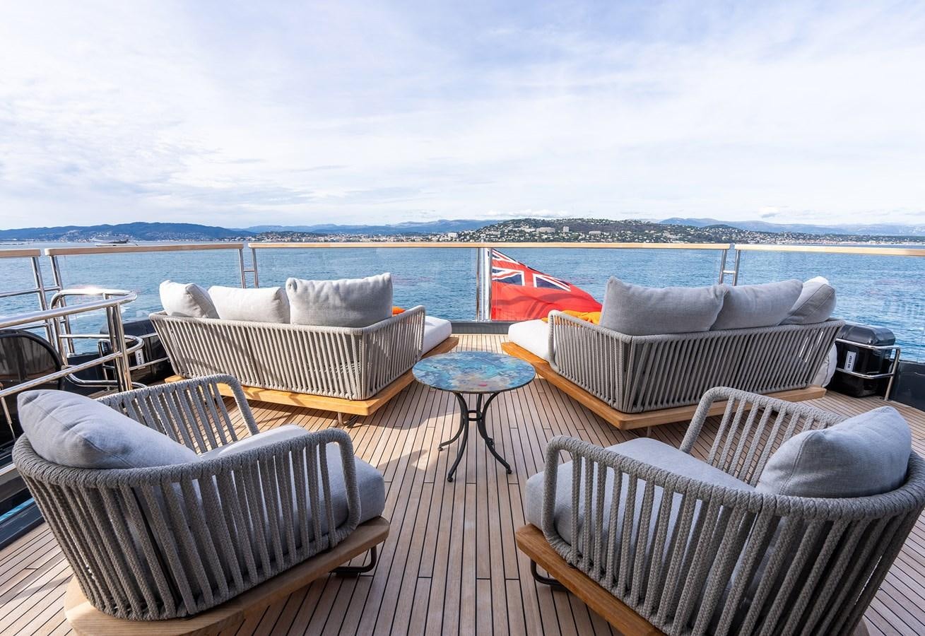 a deck with chairs and a table on it aboard MAJIC Yacht for Sale