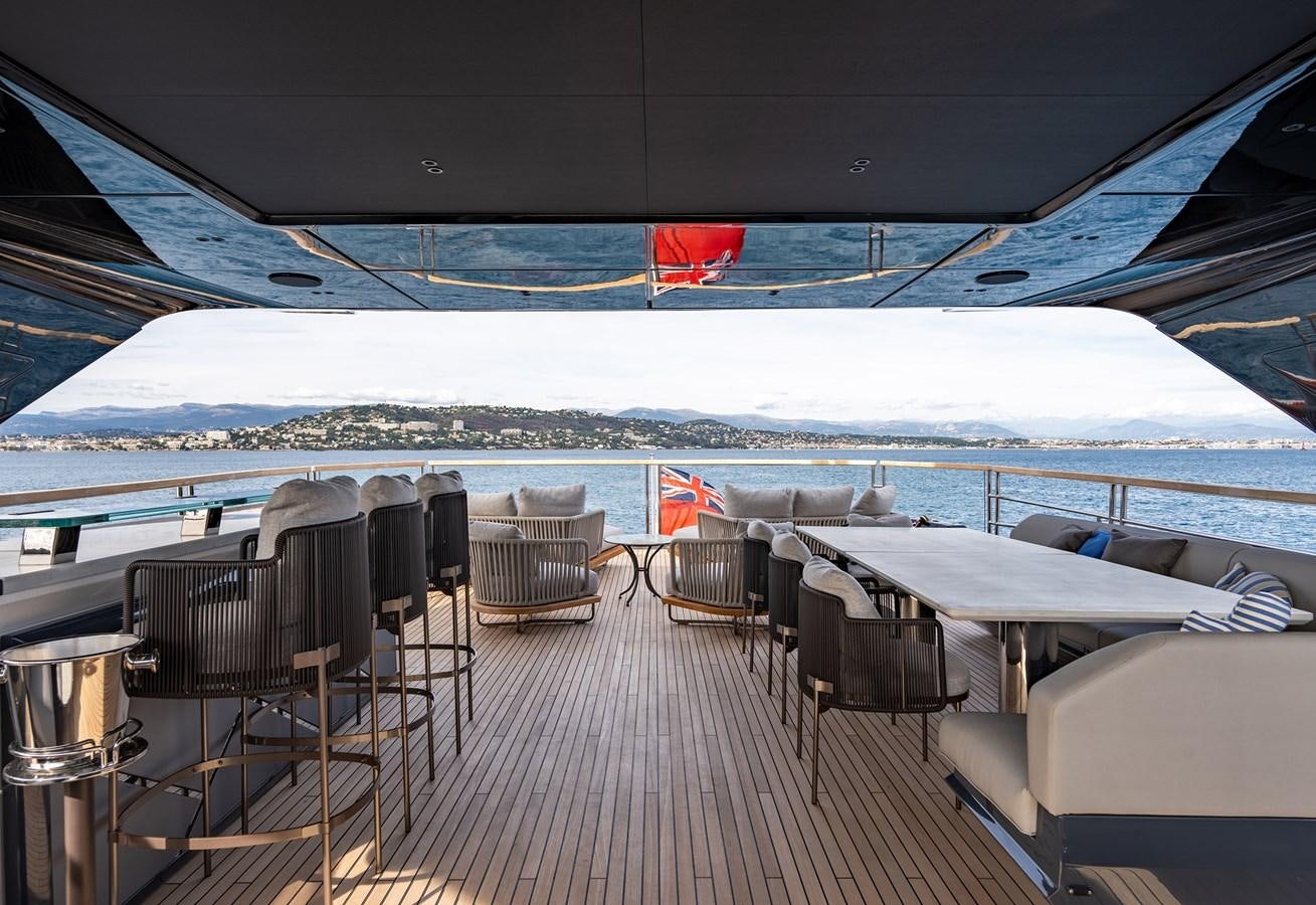 a deck with chairs and tables on it by a large body of water aboard MAJIC Yacht for Sale