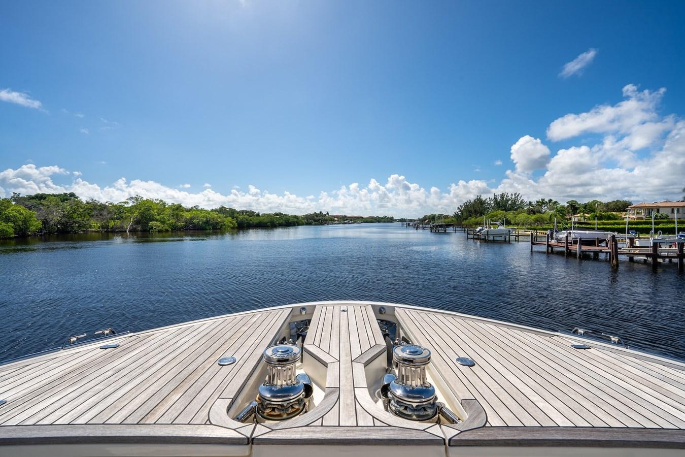 a dock with a body of water and trees in the background aboard NEVER SAY NEVER 2015/2023 Yacht for Sale