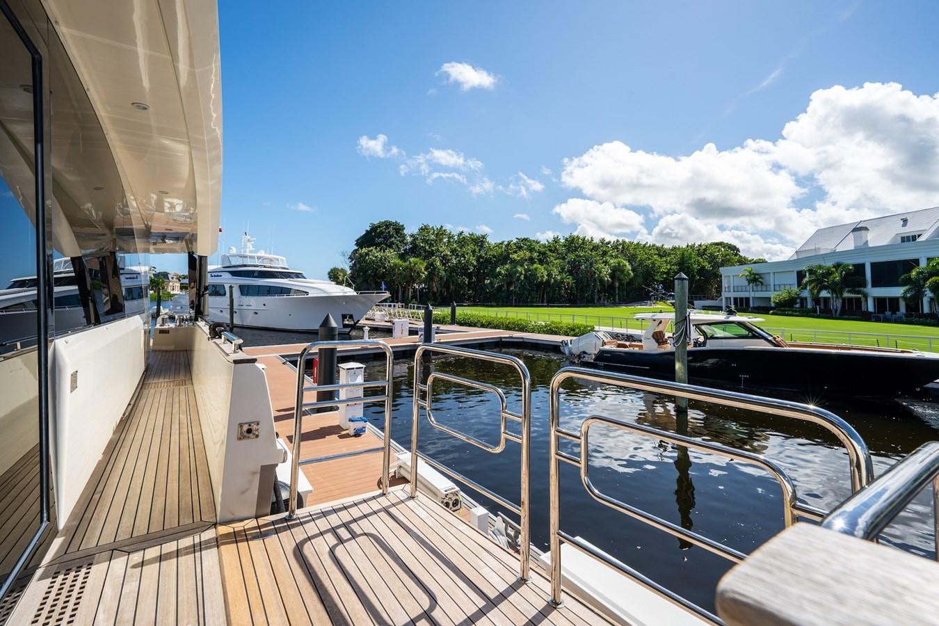 a deck with a boat and a dock with trees and buildings in the background aboard NEVER SAY NEVER 2015/2023 Yacht for Sale