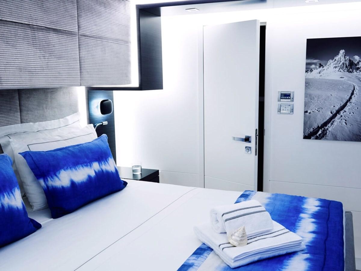 a bed with a white sheet and a blue pillow aboard BLUE DEER Yacht for Sale