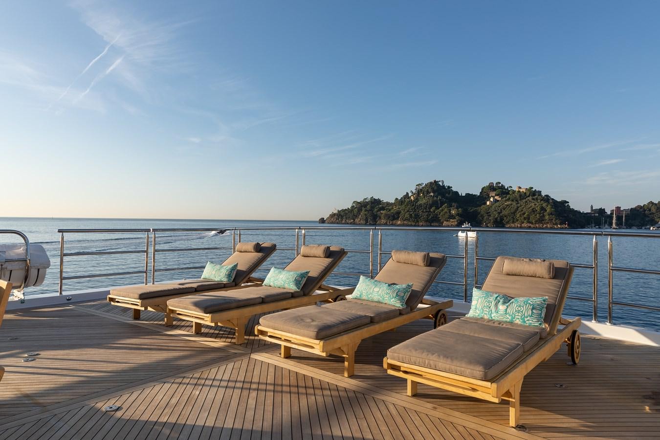 a deck with chairs and a body of water in the background aboard SKYFALL Yacht for Sale