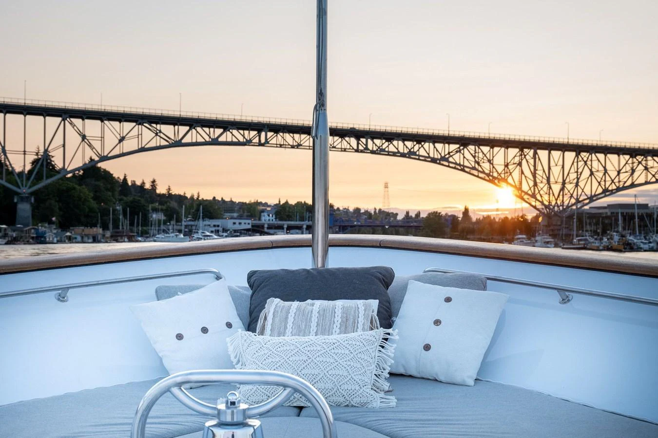 a rooftop view of a boat with pillows and a railing and a bridge in the background aboard DOZER Yacht for Sale