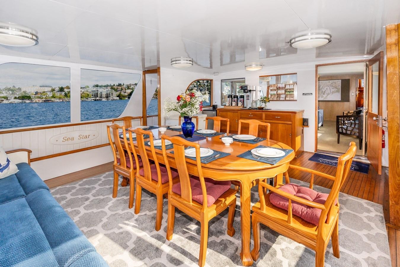 a dining table and chairs in a room with a large window aboard SEA STAR Yacht for Sale