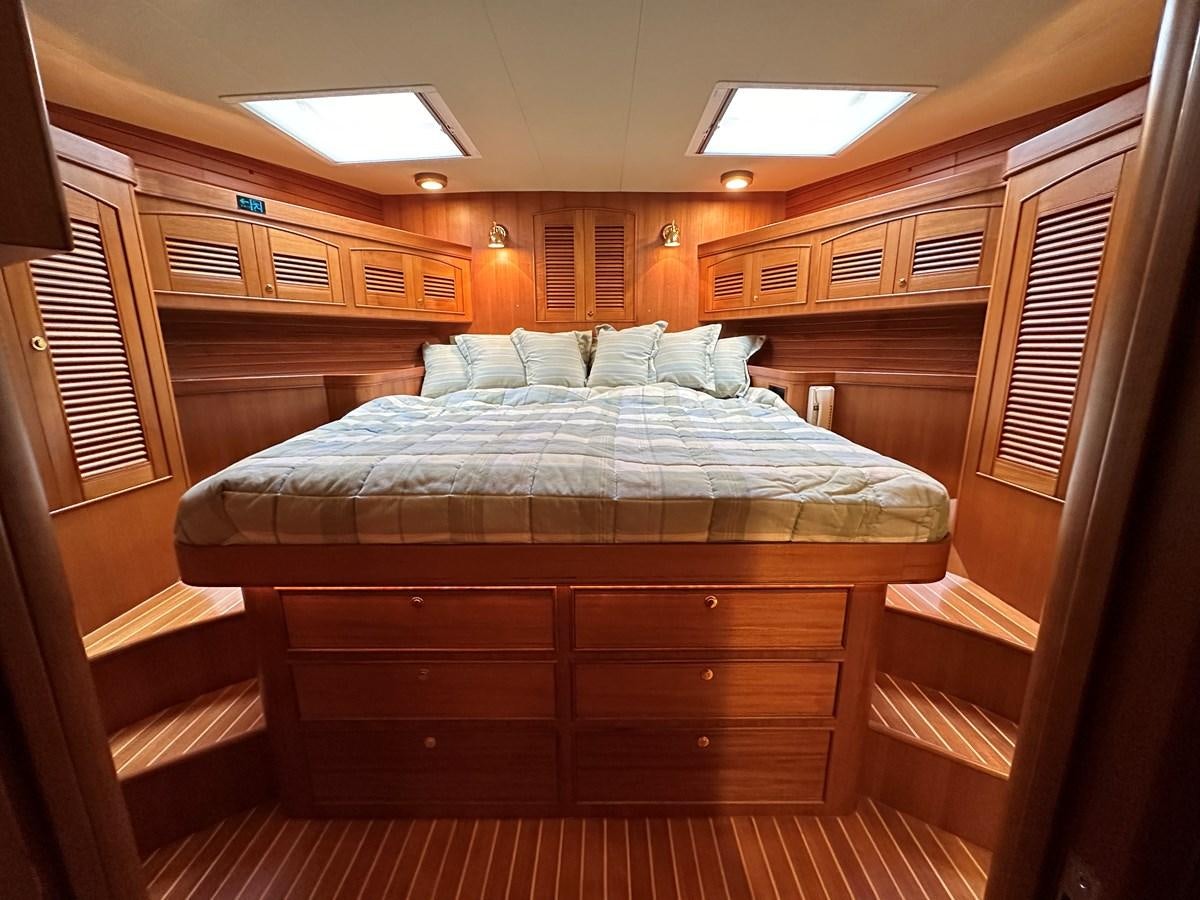 a bed with a wooden headboard aboard AZURA Yacht for Sale