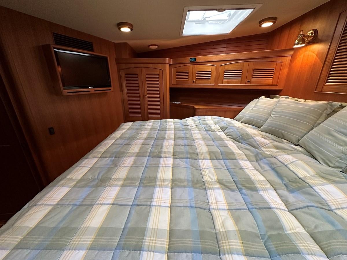 a bed with a blue comforter aboard AZURA Yacht for Sale