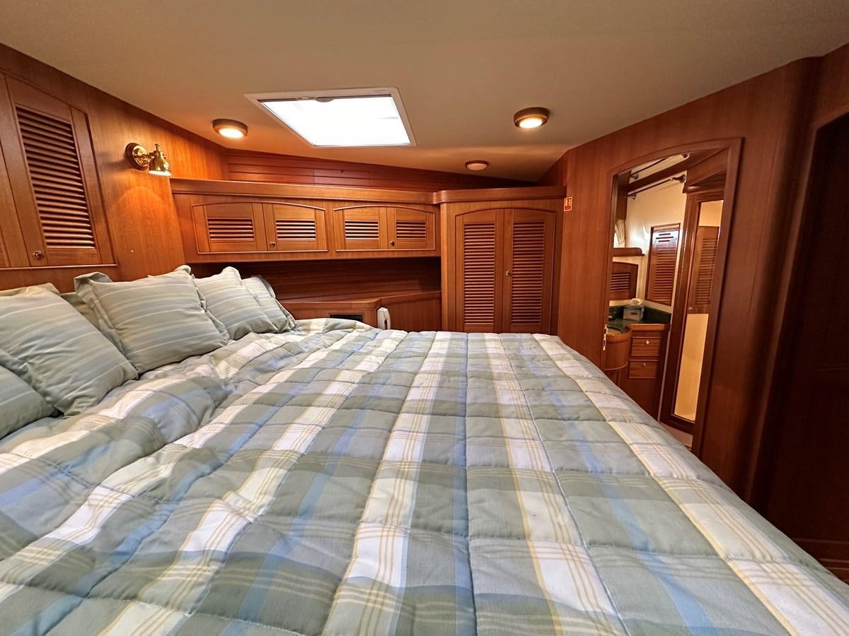 a bed with blue sheets aboard AZURA Yacht for Sale