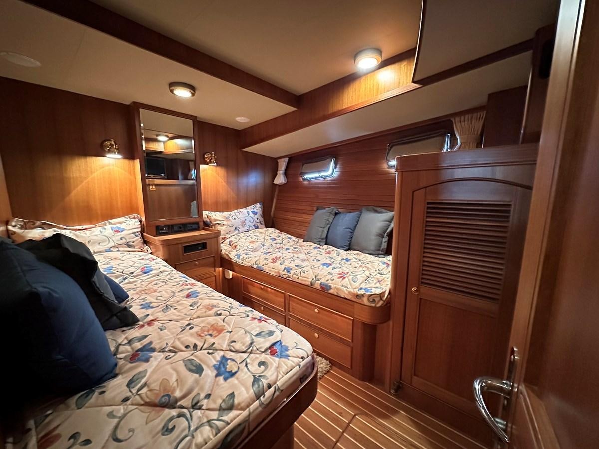 a bedroom with a bed and a dresser aboard AZURA Yacht for Sale