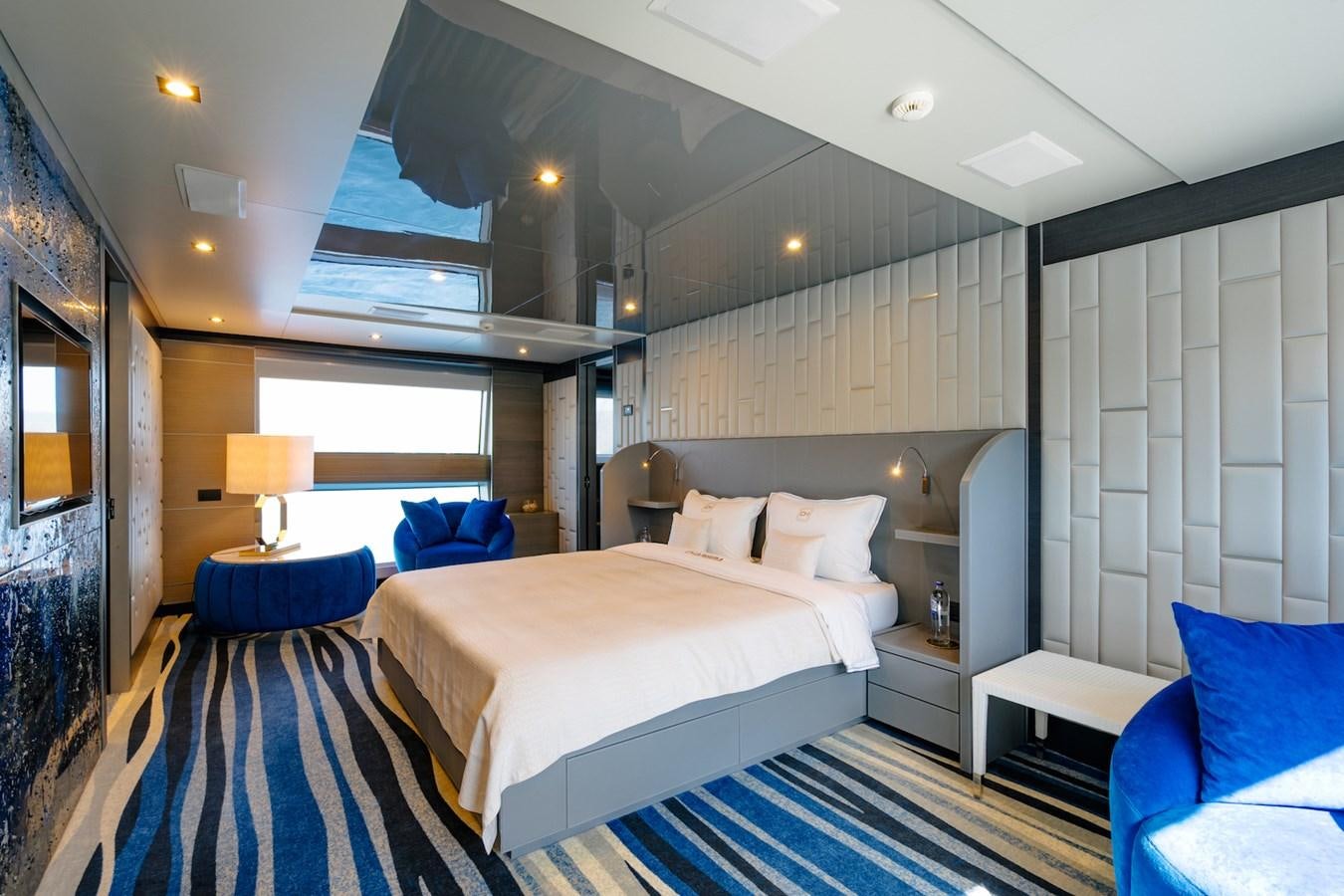 a room with a bed and a blue couch aboard CHARISMA Yacht for Sale