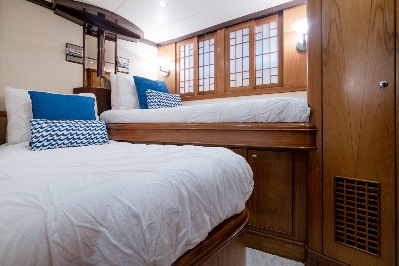 a room with a bed and a wood cabinet aboard HAPPINESS II Yacht for Sale
