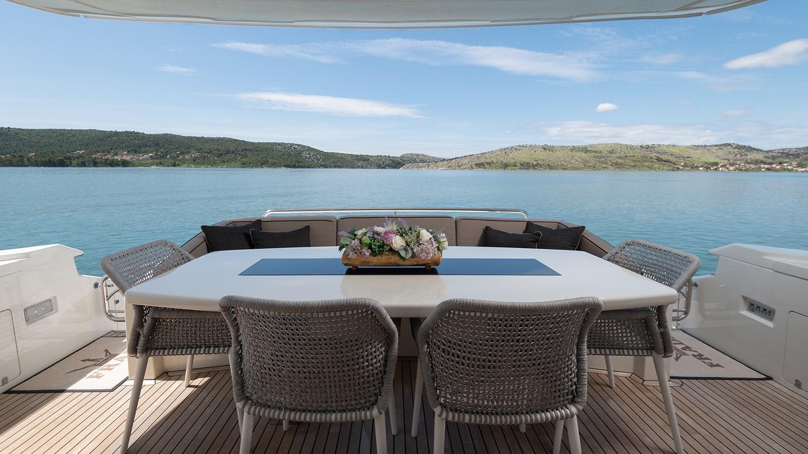 a table and chairs on a deck overlooking a body of water aboard FRADI Yacht for Sale