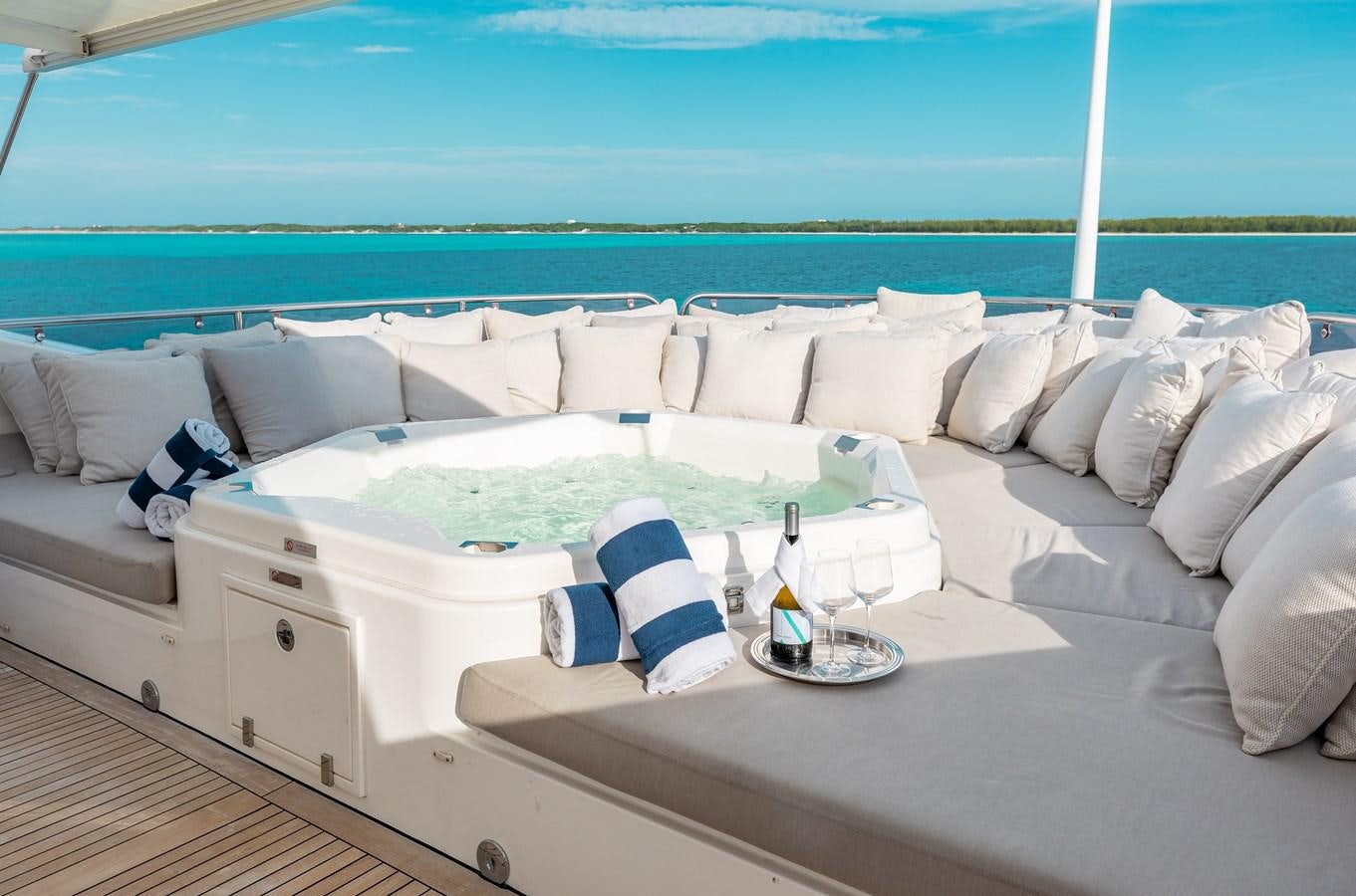 a white couch with pillows and a glass of wine on it aboard AQUARIUM Yacht for Sale