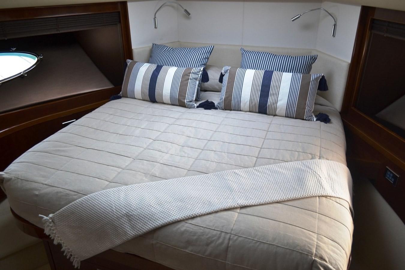a bed with a white sheet and blue and white striped pillows aboard WATCHIT Yacht for Sale