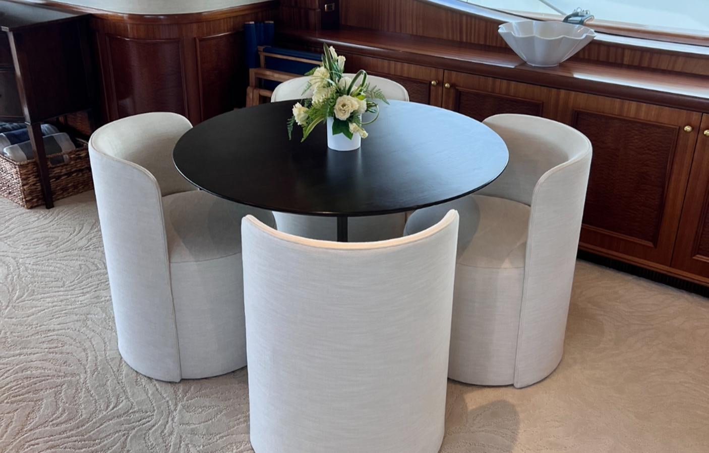 a white chair with a black table and white chairs in a room with a wood wall and a aboard MISS STEPHANIE Yacht for Sale