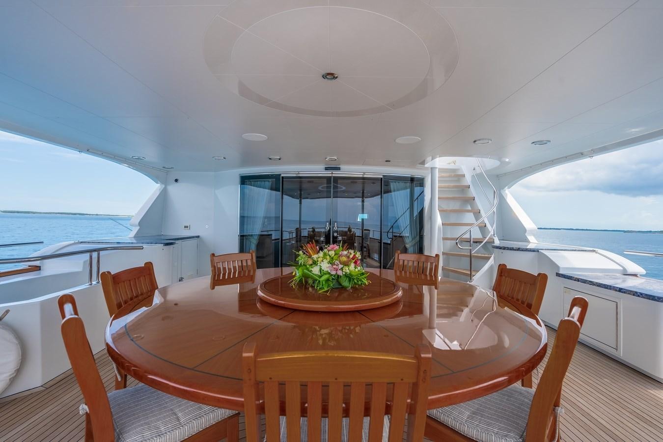 a dining table with chairs and a large window with a view of the ocean aboard MISS STEPHANIE Yacht for Sale