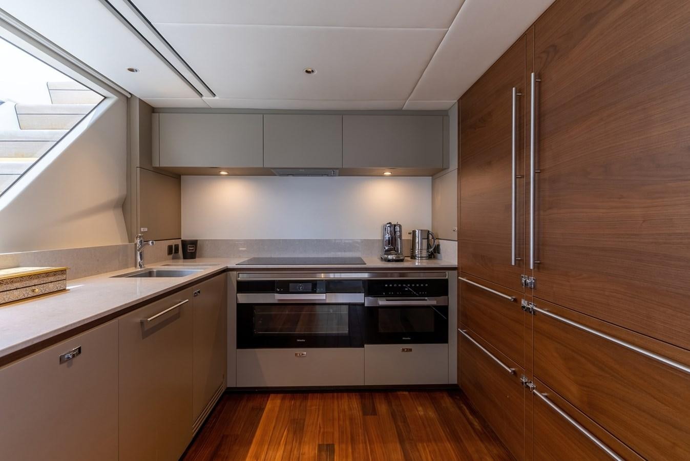 a kitchen with wooden cabinets aboard 2022 PRINCESS X95 Yacht for Sale