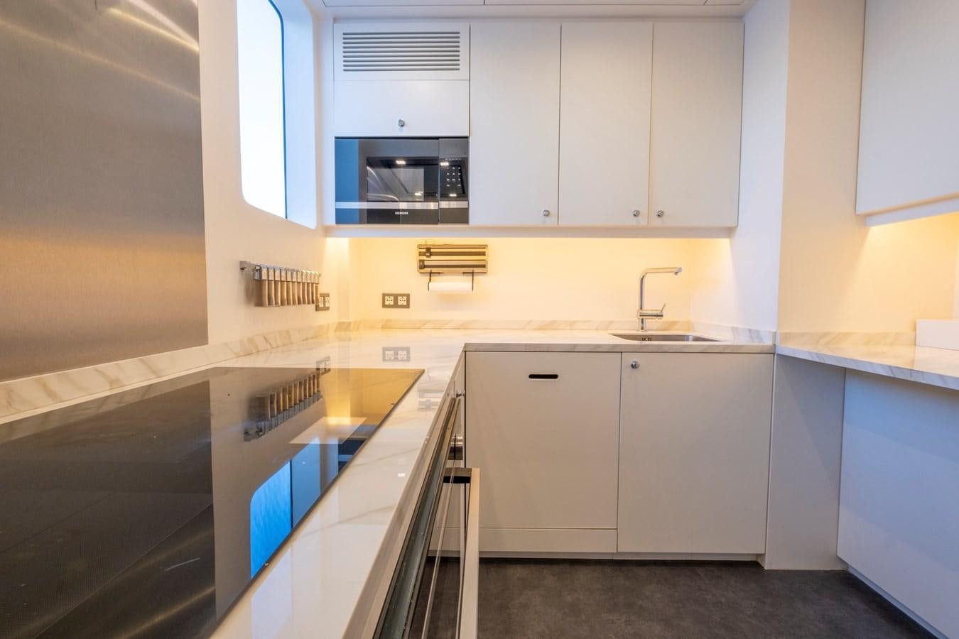 a kitchen with white cabinets aboard MURAL 85 Yacht for Sale