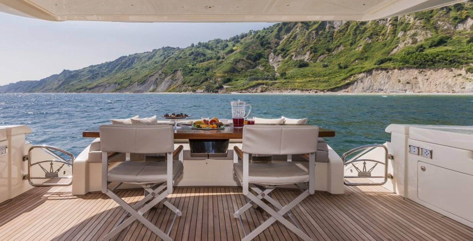 a table and chairs on a deck overlooking a body of water aboard DOLLY Yacht for Sale