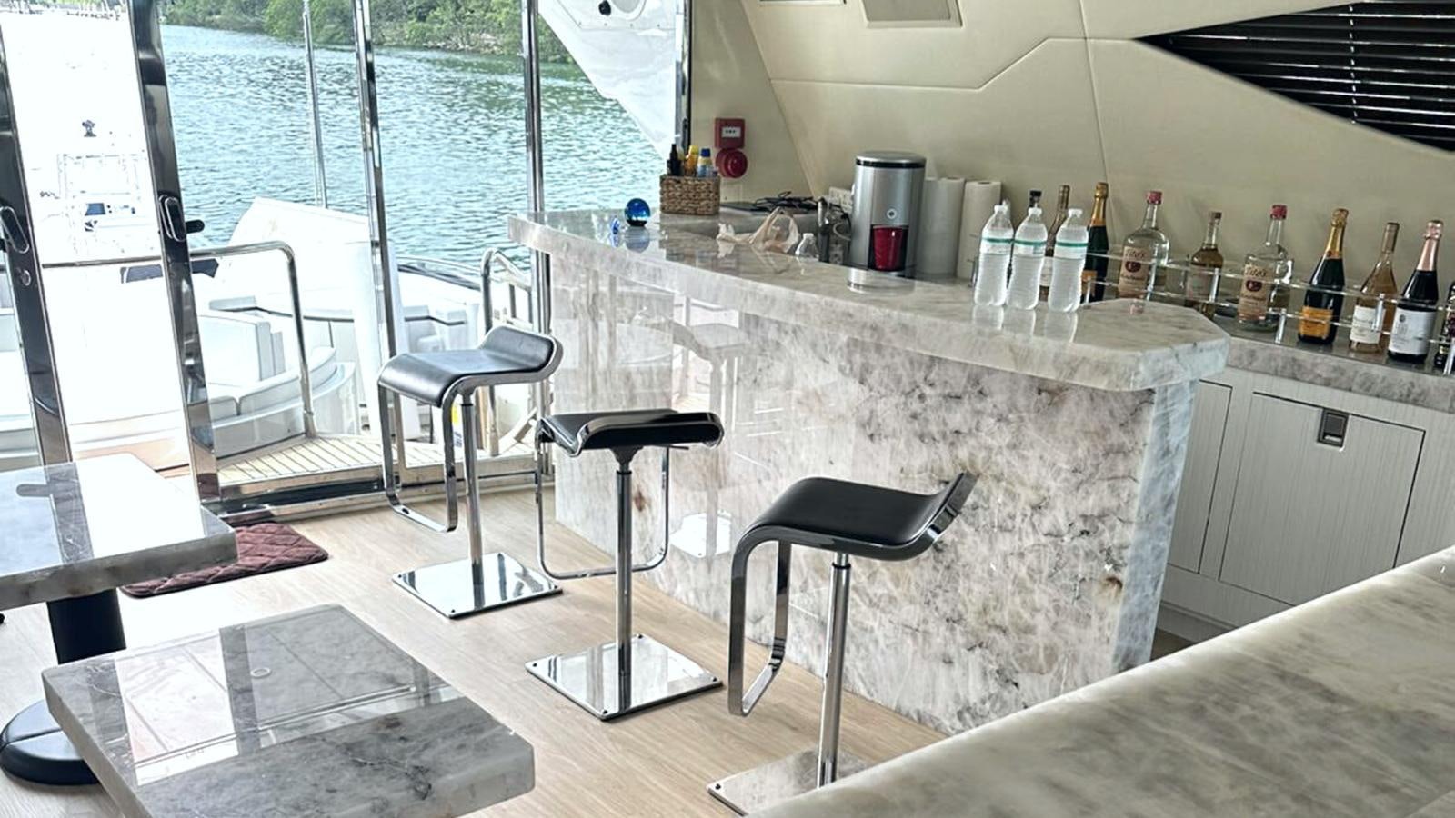 a kitchen with a bar stools and a table with chairs aboard DAYA Yacht for Sale