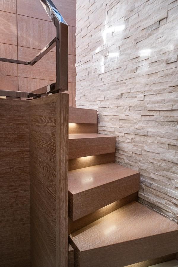 a wooden staircase with a white brick wall aboard SHEVA Yacht for Sale