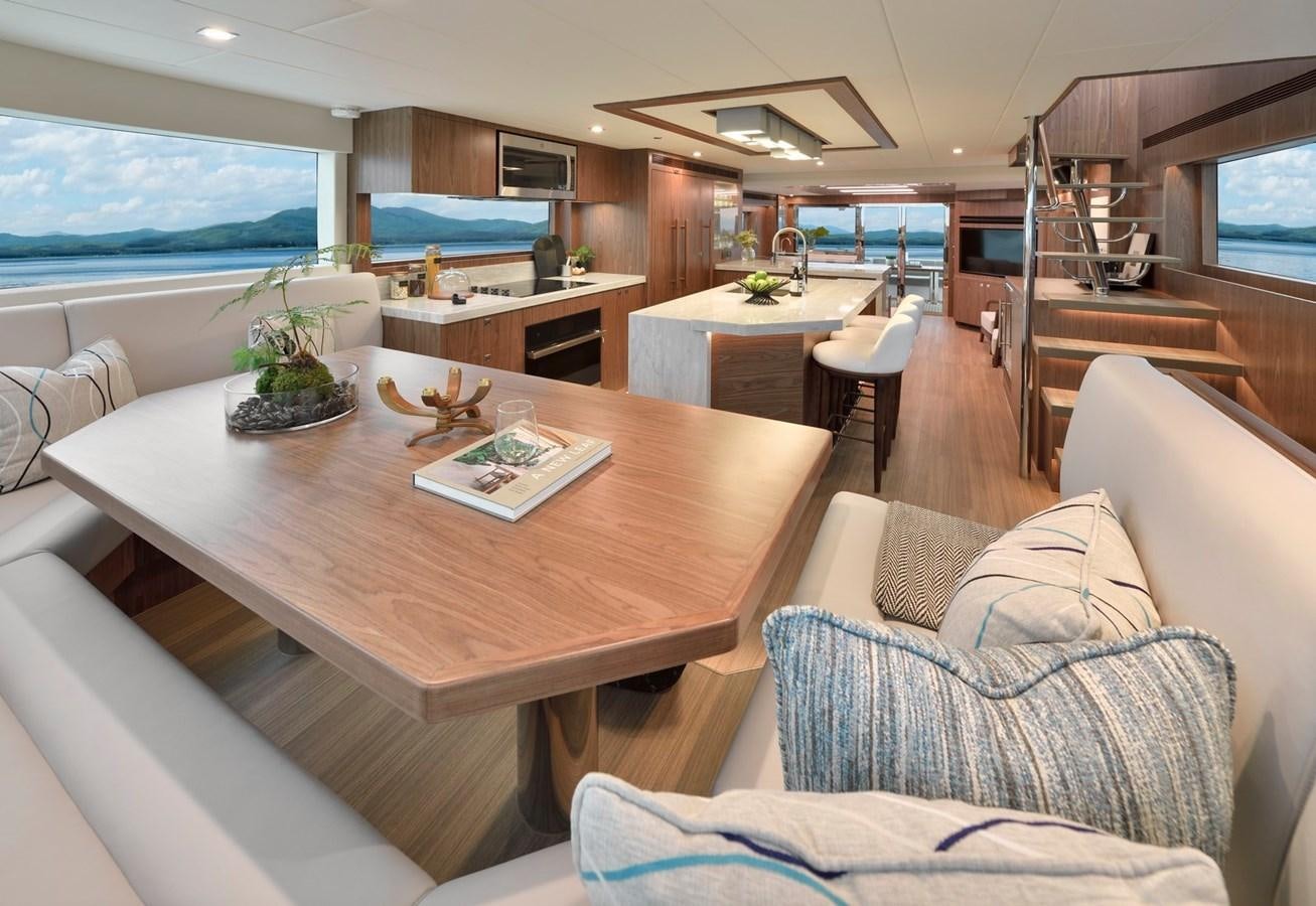 a living room with a table and couches aboard HORIZON V77 CMY / AVAILABLE NOW Yacht for Sale
