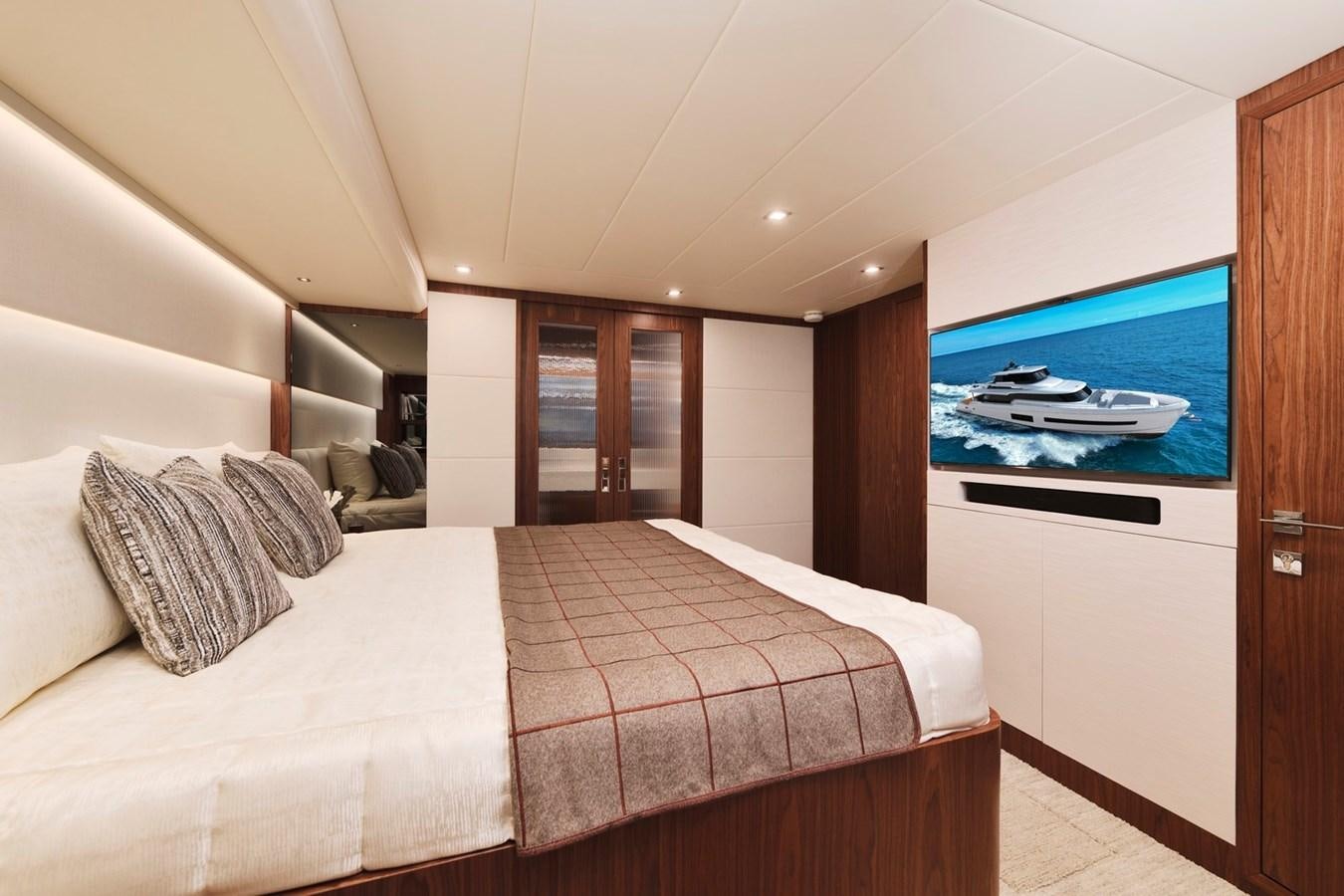 a bedroom with a bed and a television on the wall aboard HORIZON V77 CMY / AVAILABLE NOW Yacht for Sale