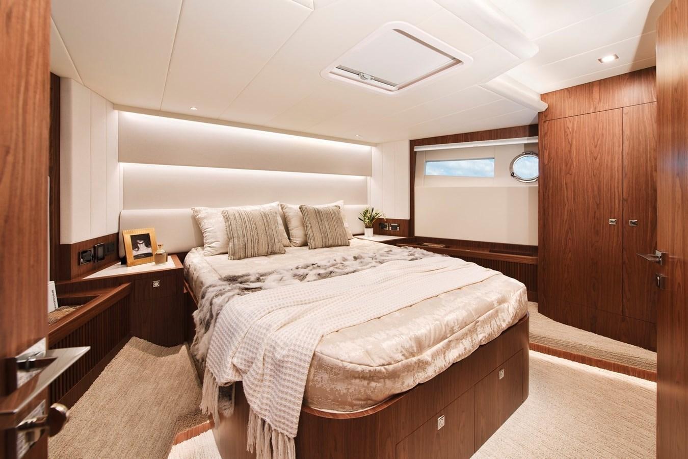 a bedroom with a bed and a wood cabinet aboard HORIZON V77 CMY / AVAILABLE NOW Yacht for Sale