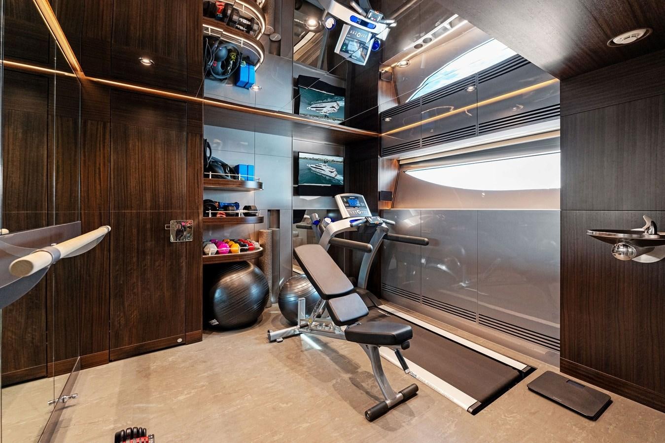 a room with a wood wall and a desk with chairs and a shelf with computer screens aboard SERENITY Yacht for Sale