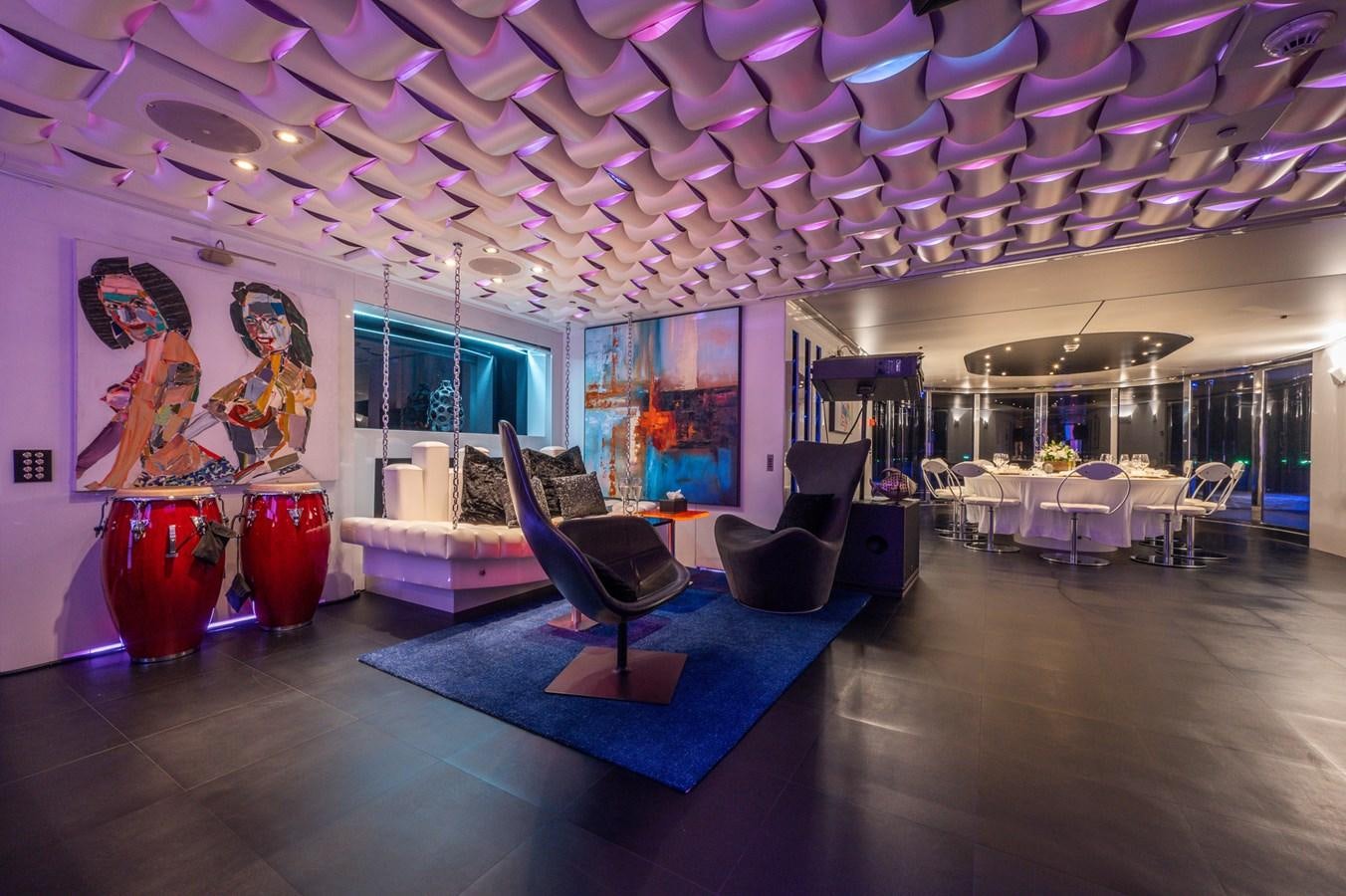 a room with a blue rug and a blue chair and a red vase with flowers on it aboard NONNI II Yacht for Sale