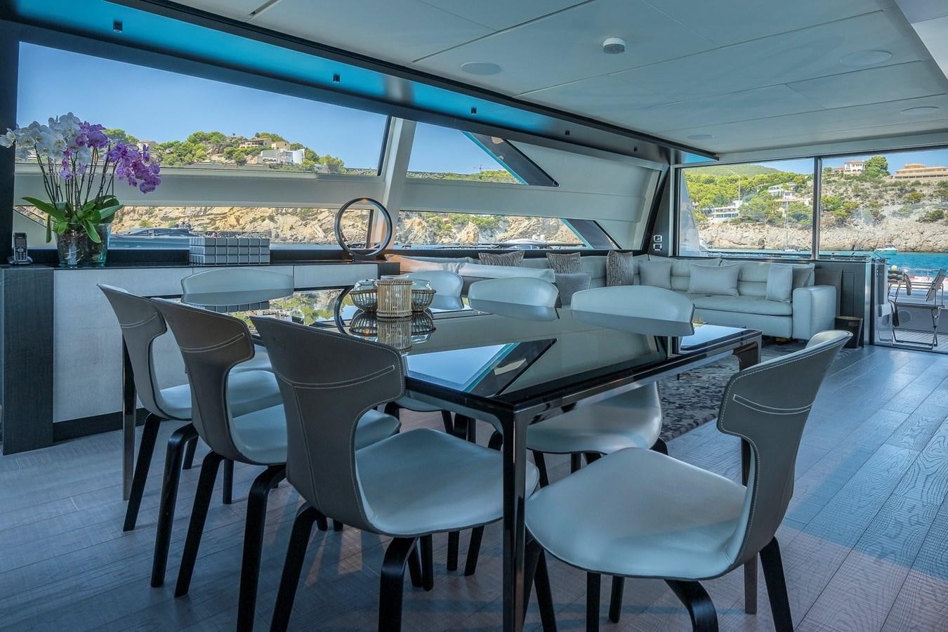 a large white table with chairs and a large window with a view of the city aboard BOMBADIL III Yacht for Sale