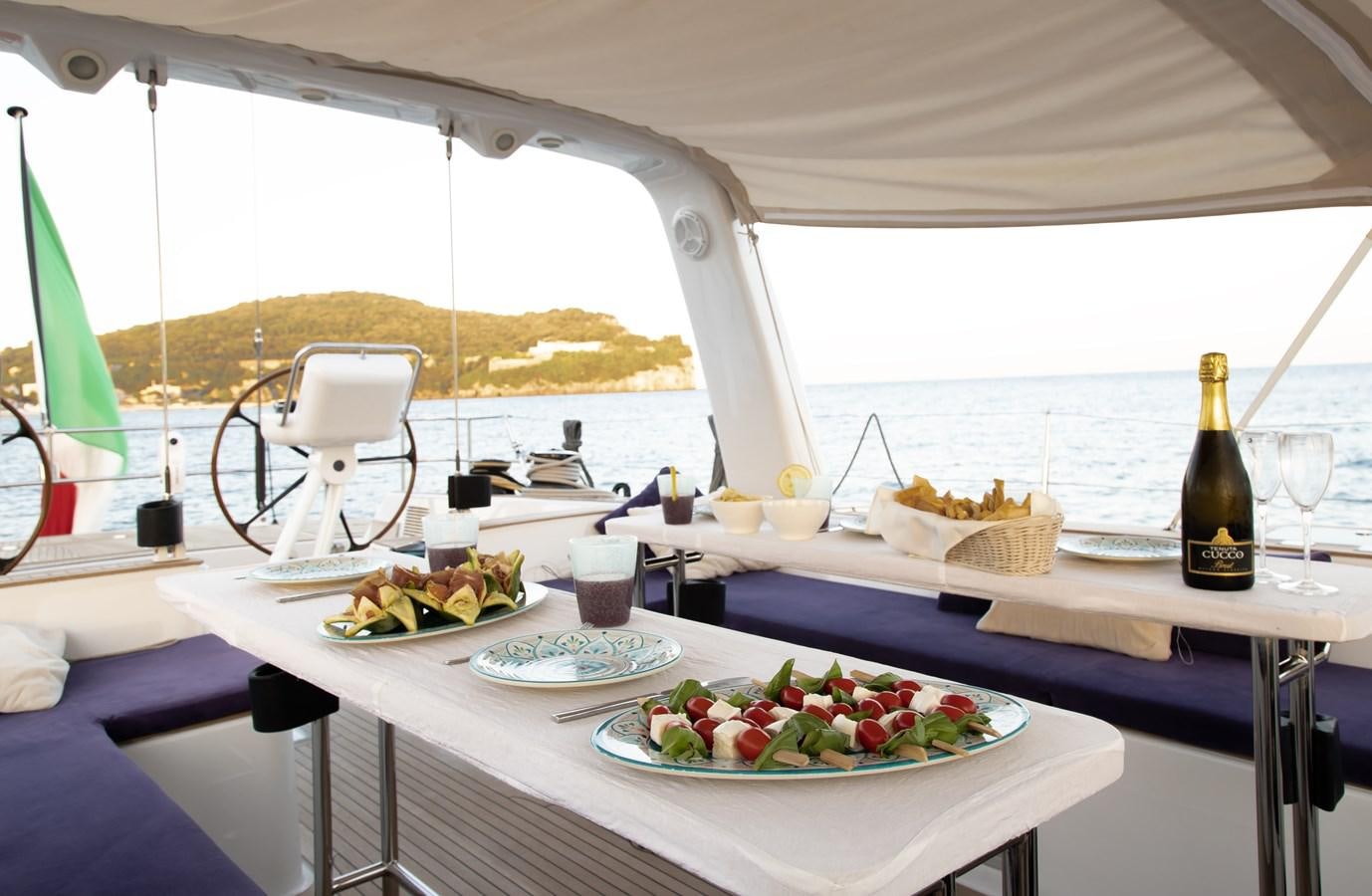 a table with plates of food and bottles of wine aboard TURCONERI Yacht for Sale