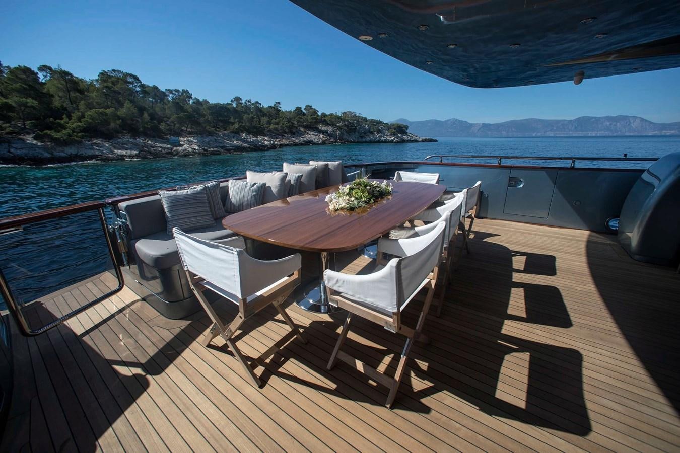 a table and chairs on a deck overlooking a body of water aboard PRINCESS L Yacht for Sale